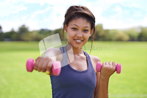 Image of Woman, portrait and dumbbells outdoor for training with smile for workout, exercise or fitness on sports field. Athlete, person and happy for physical activity or healthy body on grass with equipment