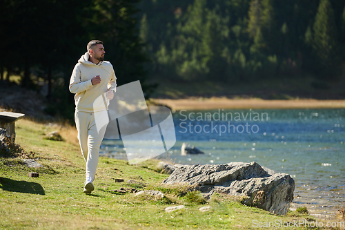 Image of Athletic man maintains his healthy lifestyle by running through the scenic mountain and lakeside environment, showcasing a commitment to fitness and well-being