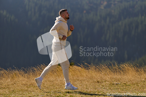 Image of A handsome man maintains his healthy lifestyle as he runs along beautiful natural trails, embodying the essence of fitness, wellness, and vitality in the midst of scenic outdoor surroundings.