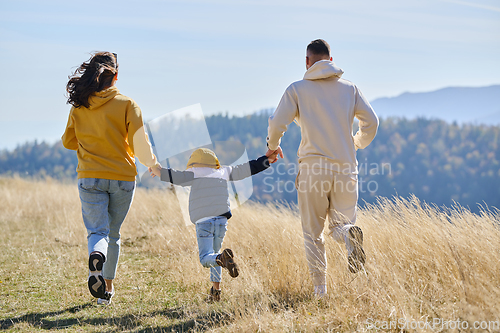 Image of A modern family, along with their son, revels in the joy of a muddy day in nature, running and playing together, encapsulating the beauty of a healthy and active lifestyle