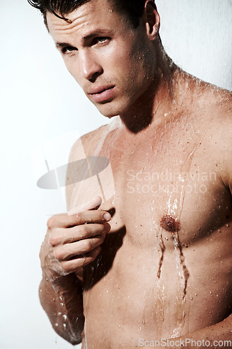 Image of Serious man in shower to relax, cleaning and body hygiene for morning skin wellness routine. Grooming, skincare and face of male model with muscle washing with water, self care and calm in bathroom.