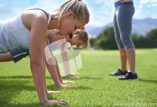 Image of Women, teamwork and push ups on grass for fitness with exercise, training and coach on sports field. Athlete, people and collaboration on ground with physical activity for healthy body and wellness