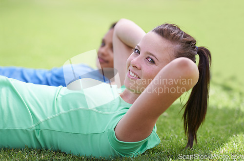 Image of Happy woman, portrait and sit ups for fitness, workout or outdoor exercise together on green grass. Young active female person or people smile for core strength, training and lying on field in nature