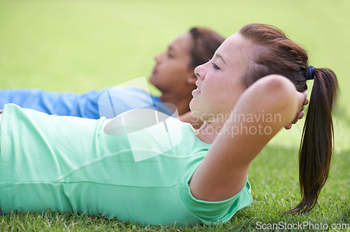 Image of Woman, sit ups and workout on green grass for fitness or outdoor exercise together in nature. Young active female person or people in core, abs or strength training while lying on field outside