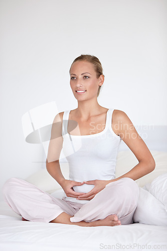 Image of Happy woman, zen and relax on bed for morning, health or wakeup in calm comfort at home. Young female person holding stomach or tummy in zen, meditation or awareness sitting in bedroom at house