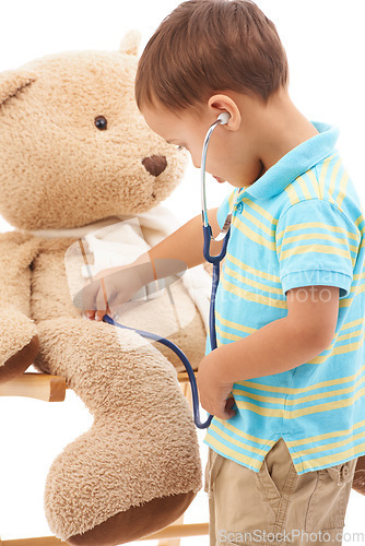 Image of Boy child, teddy bear and stethoscope in studio for playing doctor, listening and wellness by white background. Kid, healthcare game and development with plushie toys, medical check or consultation