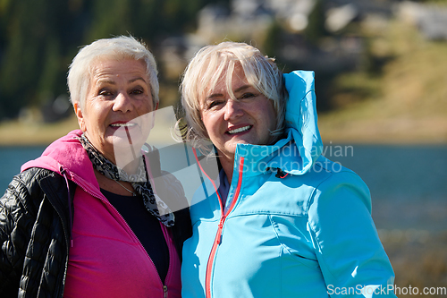 Image of Senior women hikers standing on mountain enjoying a trekking day - Smiling climbing tourists enjoying holidays and healthy lifestyle - Freedom, success sport concept