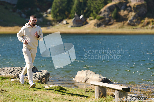 Image of Athletic man maintains his healthy lifestyle by running through the scenic mountain and lakeside environment, showcasing a commitment to fitness and well-being