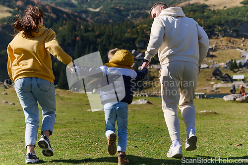 Image of A modern family, along with their son, revels in the joy of a muddy day in nature, running and playing together, encapsulating the beauty of a healthy and active lifestyle