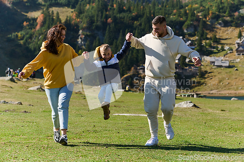 Image of A modern family, along with their son, revels in the joy of a muddy day in nature, running and playing together, encapsulating the beauty of a healthy and active lifestyle