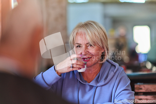 Image of Elderly woman savors the serenity of the morning as she enjoys a cup of coffee on the porch of her rustic cottage, finding solace in the simplicity of nature and contemplative moments