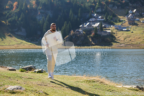Image of Athletic man maintains his healthy lifestyle by running through the scenic mountain and lakeside environment, showcasing a commitment to fitness and well-being