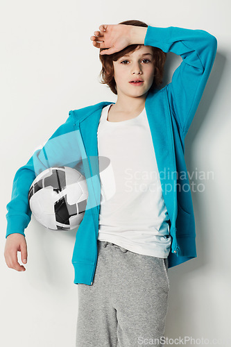Image of Soccer, casual and portrait of teenager in a studio for sports training or exercise with style. Serious, fashion and boy kid athlete with football confidence and trendy outfit by white background.