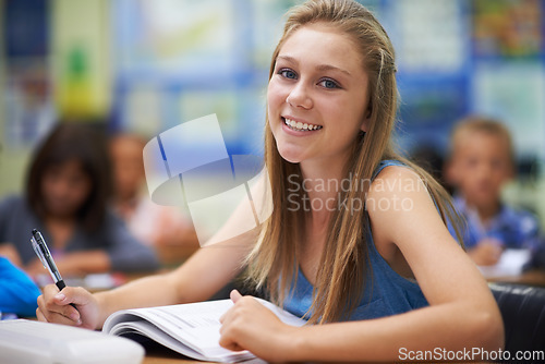 Image of Girl, classroom and writing in portrait for education, learning and notes for knowledge in high school. Female person, book and pride for assessment or test, studying lesson and happy at academy