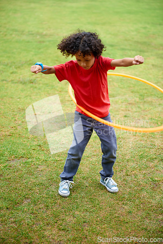 Image of Child, playing and hula hoop on field on holiday, green grass and sunshine with energy in city. Young boy, mexican and game on playground, summer break and leisure with wellness in urban town