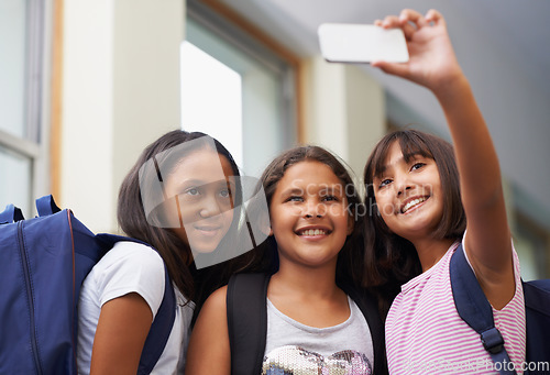 Image of Friends, children and smile for selfie in elementary school lobby for fun educational memory together. Group of students, young girls and kids taking picture for social media, photography or learning