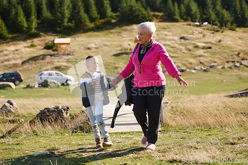 Image of Elderly grandmother and her grandchild share a leisurely stroll through nature, enveloped in the beauty of their surroundings, fostering a bond that transcends generations