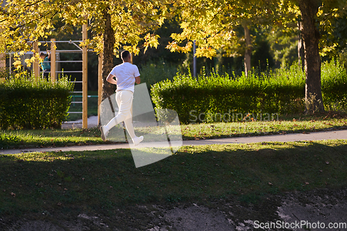 Image of A handsome man maintains his healthy lifestyle as he runs along beautiful natural trails, embodying the essence of fitness, wellness, and vitality in the midst of scenic outdoor surroundings.