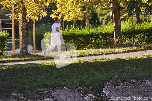 Image of A handsome man maintains his healthy lifestyle as he runs along beautiful natural trails, embodying the essence of fitness, wellness, and vitality in the midst of scenic outdoor surroundings.