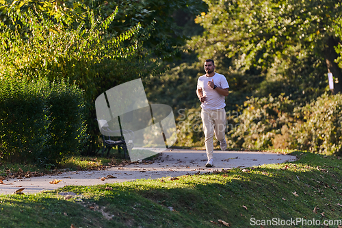 Image of A handsome man maintains his healthy lifestyle as he runs along beautiful natural trails, embodying the essence of fitness, wellness, and vitality in the midst of scenic outdoor surroundings.