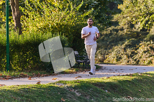 Image of A handsome man maintains his healthy lifestyle as he runs along beautiful natural trails, embodying the essence of fitness, wellness, and vitality in the midst of scenic outdoor surroundings.