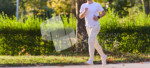 Image of A handsome man maintains his healthy lifestyle as he runs along beautiful natural trails, embodying the essence of fitness, wellness, and vitality in the midst of scenic outdoor surroundings.