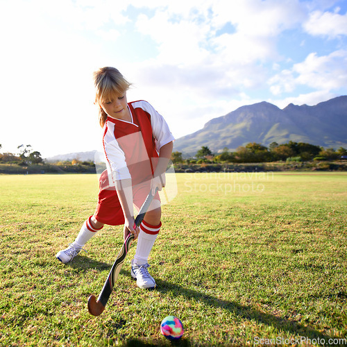 Image of Girl, green grass and playing hockey for game, outdoor match or sports in nature for practice. Female person, kid or playful child enjoying competition with ball on field for fitness or training