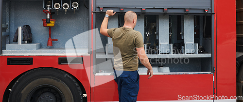 Image of A dedicated firefighter preparing a modern firetruck for deployment to hazardous fire-stricken areas, demonstrating readiness and commitment to emergency response