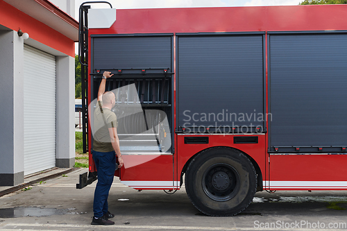 Image of A dedicated firefighter preparing a modern firetruck for deployment to hazardous fire-stricken areas, demonstrating readiness and commitment to emergency response