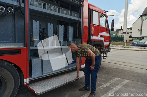 Image of A dedicated firefighter preparing a modern firetruck for deployment to hazardous fire-stricken areas, demonstrating readiness and commitment to emergency response