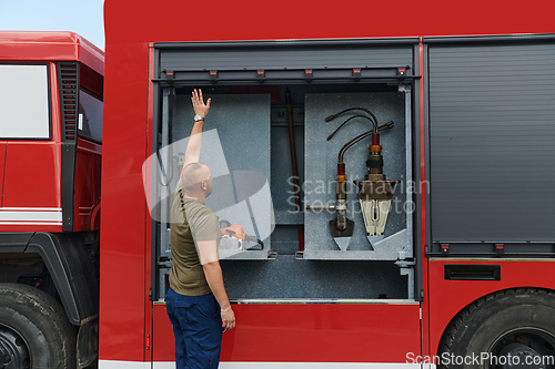 Image of A dedicated firefighter preparing a modern firetruck for deployment to hazardous fire-stricken areas, demonstrating readiness and commitment to emergency response