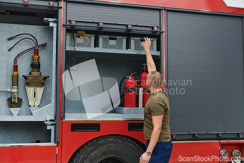 Image of A dedicated firefighter preparing a modern firetruck for deployment to hazardous fire-stricken areas, demonstrating readiness and commitment to emergency response