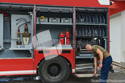 Image of A dedicated firefighter preparing a modern firetruck for deployment to hazardous fire-stricken areas, demonstrating readiness and commitment to emergency response