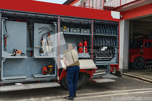Image of A dedicated firefighter preparing a modern firetruck for deployment to hazardous fire-stricken areas, demonstrating readiness and commitment to emergency response