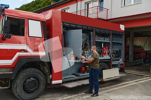 Image of A dedicated firefighter preparing a modern firetruck for deployment to hazardous fire-stricken areas, demonstrating readiness and commitment to emergency response