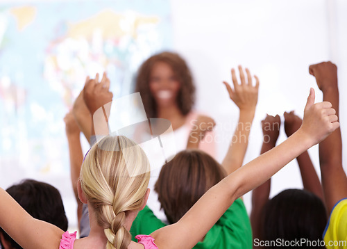 Image of Happy woman, teacher and students with question in classroom, presentation or lesson at school. Female person, educator or lecturer with group of learners with hands raised for interaction in class
