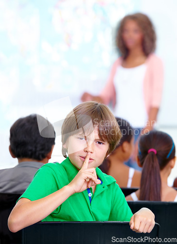 Image of Portrait, student or child in classroom with hush, gossip or fingers on lips for quiet learning. Sign, study or boy learner with whisper or shush gesture for rumor, loud noise or silence in school