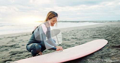 Image of Surfing, beach and woman with wax for surfboard for water sports, fitness and freedom by ocean. Nature, travel and happy Japanese person on sand for wellness on holiday, vacation and adventure by sea