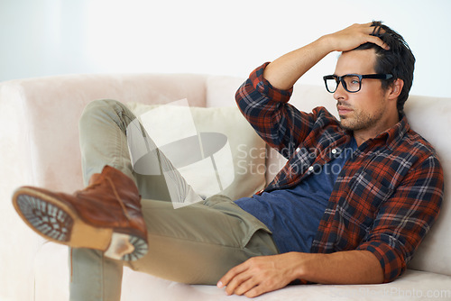 Image of Stress, thinking and man with anxiety on sofa in home with depression or crisis in mental health. Frustrated, person or worry for budget of finance, money or debt from unemployment or remember trauma