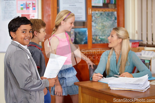 Image of Teacher, portrait or happy kids talking in classroom for education, learning or tutoring at school. Woman, smile or educator helping a group of young students or children with paperwork for studying