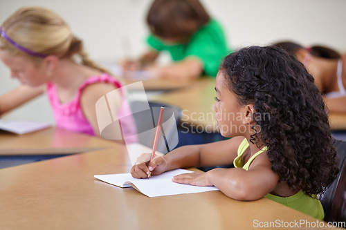 Image of School, girl and writing in book in classroom for education, studying lesson or learning assessment at desk. Children, student or kids drawing in notebook for academic development, test or knowledge