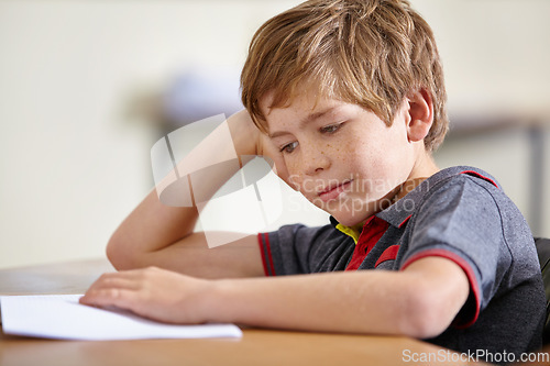 Image of Class, notebook and bored child at desk, learning and education with school exam. Reading book, studying for test and boy student in classroom with knowledge and thinking with depression on project.