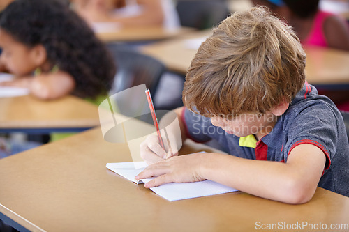 Image of School, boy and kid writing in notebook in classroom, desk and studying for education, knowledge and academic assessment. Child, student and drawing in book for learning lesson, test and development