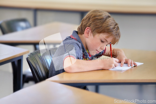 Image of Boy, notebook and writing in school, classroom or studying academic assessment, learning lesson or test at table. Student, child and kid drawing notes on paper for education, development or knowledge