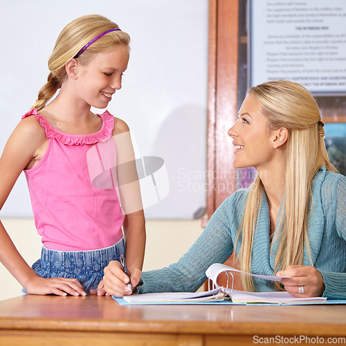 Image of Teacher, student and grading paper in classroom, education and learn with portfolio, mark test or feedback. Teaching for development, exam and study, explain subject with woman and girl kid in class