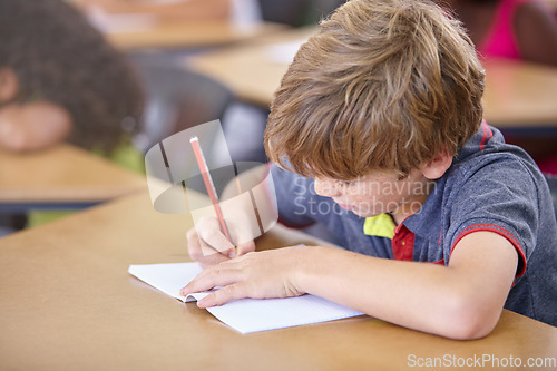 Image of School, boy and writing in book in classroom, desk and studying for education, knowledge and learning assessment. Child, kid and student drawing in notebook for academic development, test and lesson