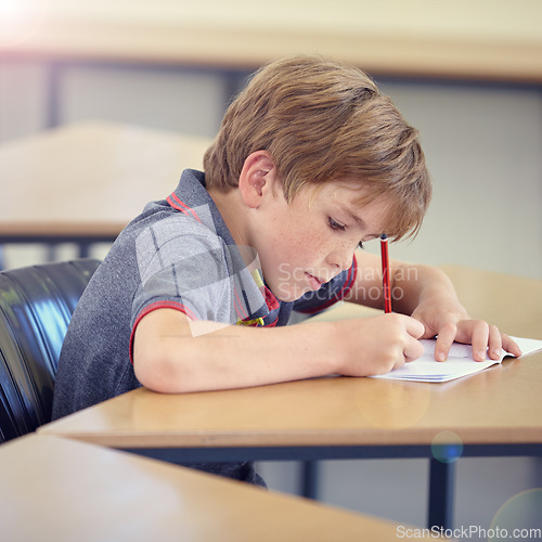 Image of Child, student and writing in classroom for learning, education and development in language quiz or test. Smart boy or kid with notebook for school progress, creativity and knowledge at his desk