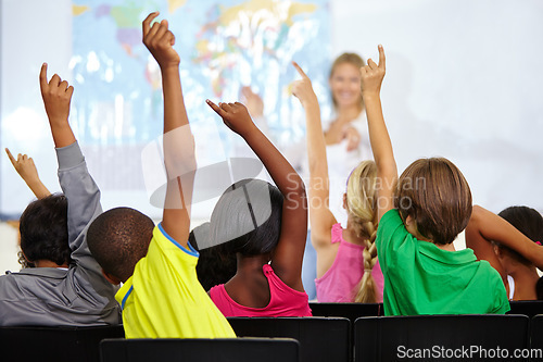 Image of Back of children, teacher and raise hands for questions, education or learning with geography quiz in classroom. Youth, group of students and school for teaching support, map ideas and answer or yes