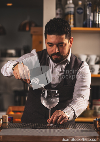 Image of Barman putting ice cubes into glass