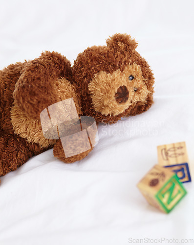 Image of Teddy bear, toys and closeup in bedroom with building blocks on a mattress for still life of development. Learning, letters and objects for childcare and play in home with soft animal and alphabet